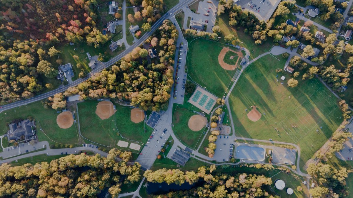 Aerial view of the town recreation park in autumn, showing ball fields, tennis courts, a pool and the surrounding woodland.